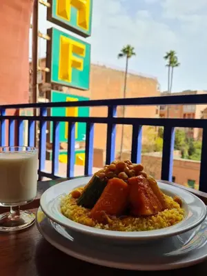 a plate of food on a table with a glass of milk at Hotel Tachfine in Marrakech