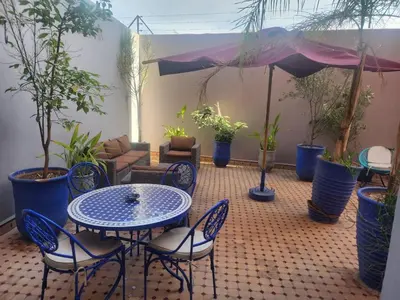 a patio with a table and chairs and potted plants at Appartement Centre Gueliz Hanane in Marrakech