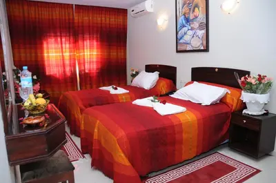 two beds in a room with red and orange blankets at Residence Hotel Assounfou in Marrakech