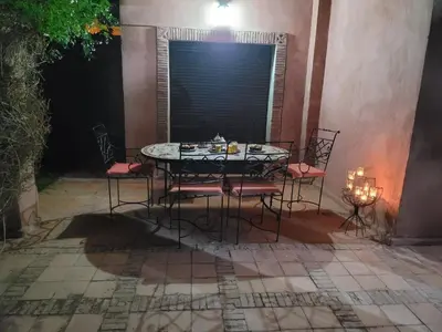 a table and chairs sitting on a patio at night at Magnifique Appt Atlas Golf Resort Marrakech in Marrakech
