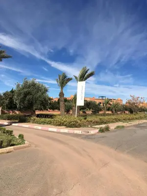 a street with palm trees and a sign next to a road at Magnifique Appt Atlas Golf Resort Marrakech in Marrakech
