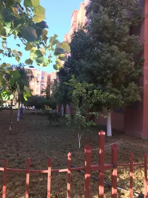 a red fence in a park with trees at Theresa apartments in Marrakech