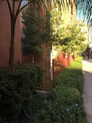 a fence next to a building with trees and bushes at Theresa apartments in Marrakech