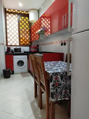 a kitchen with red cabinets and a table with chairs at Theresa apartments in Marrakech