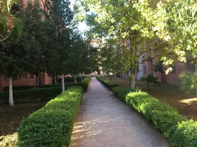 a path through a park with trees and a building at Theresa apartments in Marrakech