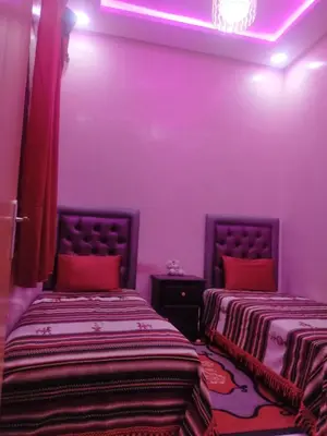 two beds in a room with purple lighting at Theresa apartments in Marrakech