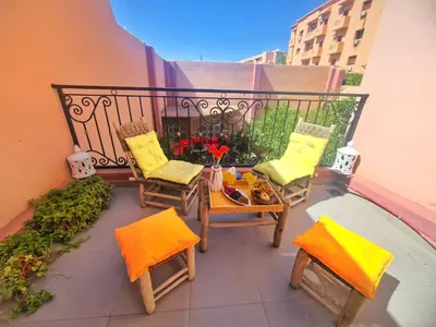 a balcony with chairs and a table with food on it at Oranger Family House Marrakech City Center in Marrakech