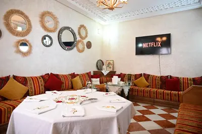 a restaurant with a table and couches in a room at Riad SARSAR airport in Marrakech