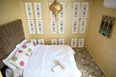 a bedroom with a bed with white sheets and pillows at Riad SARSAR airport in Marrakech