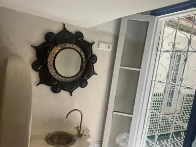a mirror hanging on a wall next to a sink at Dar Sarsar Artistic Music in Marrakech