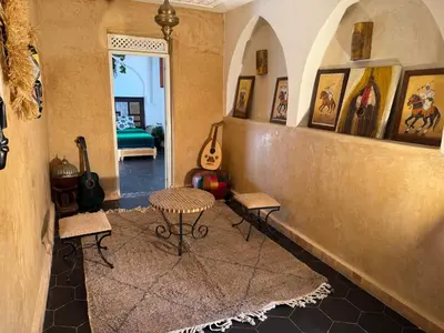 a room with a table and chairs and a room with guitars at Riad Sarsar Dar dmana in Marrakech
