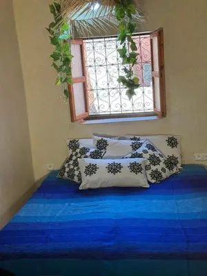 a bedroom with a blue bed with pillows and a window at Riad Sarsar Dar dmana in Marrakech