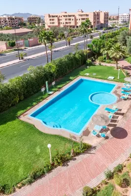 an overhead view of a swimming pool with lawn chairs and palm trees at Majorelle family residence in Marrakech