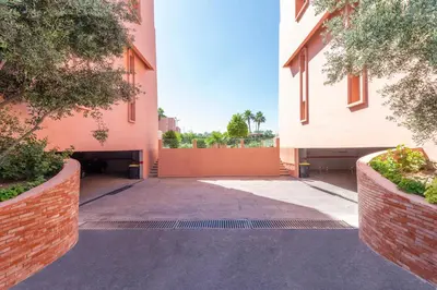 an empty alley way between two buildings with trees at Majorelle family residence in Marrakech