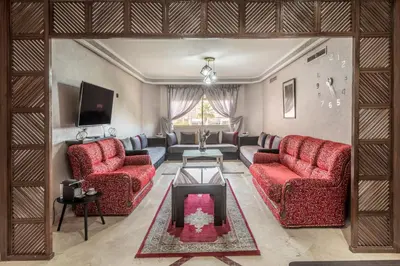 a living room with two red chairs and a tv at Majorelle family residence in Marrakech