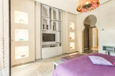a bedroom with a purple bed and a tv at Villa YENMOZ en exclusivité avec piscine privée dans la Palmeraie in Douar Caïd Layadi