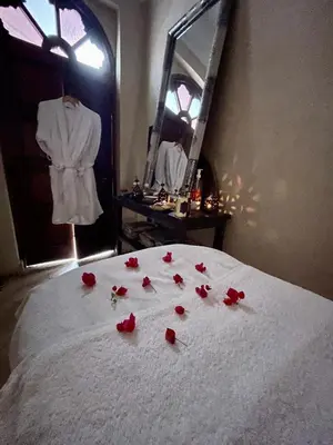 a pile of red roses on a bed with a mirror at Riad Elias & Spa in Marrakech