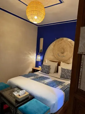 a bedroom with a large bed and a blue wall at Riad Zahri in Marrakech