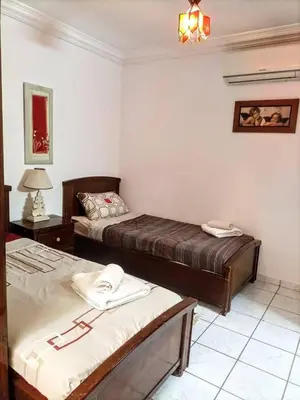 a bedroom with two beds and a table with a lamp at Riad familiale à Marrakech in Marrakech
