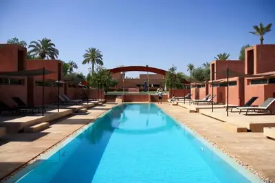 a swimming pool at a resort with chairs and palm trees at Dar Sabra in Marrakech