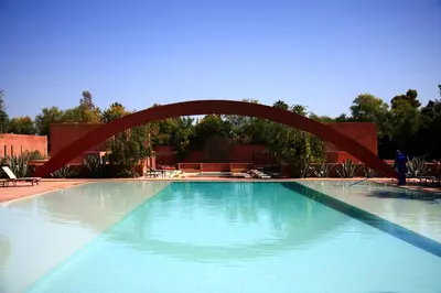 a large swimming pool with a red arch over it at Dar Sabra in Marrakech