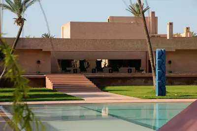 a building with a swimming pool and palm trees at Dar Sabra in Marrakech