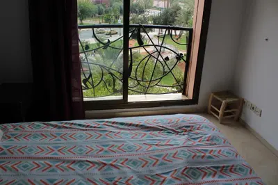 a bedroom with a bed and a window with a bike outside at La Fontaine in Marrakech