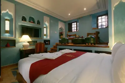 a bedroom with a large bed with blue walls and windows at Riad Omara al Kasbah in Marrakech