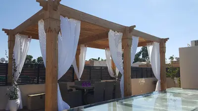 a wooden pergola with white curtains on a patio at Riad Tsar Mimoun in Marrakech