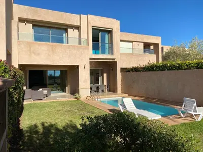 a house with a swimming pool and two lawn chairs at Villa prestige in Marrakech