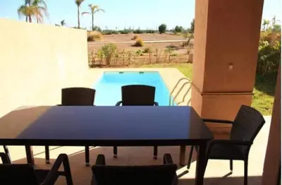 a table and chairs in front of a swimming pool at Villa prestige in Marrakech