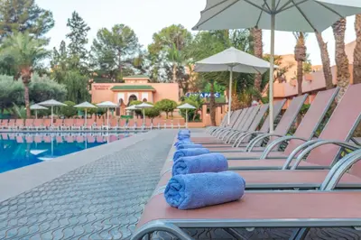 a row of chairs with blue pillows on them next to a pool at Rose Aqua Park Hotel in Marrakech