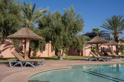 a swimming pool with chairs and umbrellas next to a resort at Maison Ayda in Marrakech