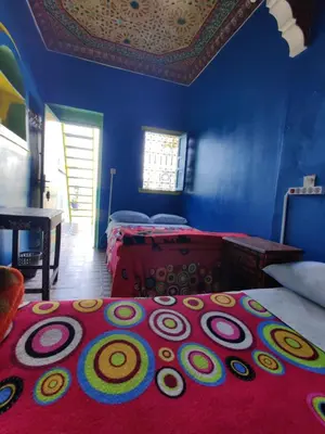 a blue room with a bed with a red rug at Hotel Medina in Marrakech