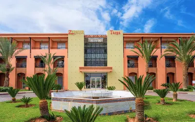 a building with palm trees in front of it at Zephyr Targa Marrakech in Marrakech