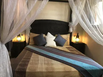 a bedroom with a bed with curtains and two lamps at Riad Côté palmeraie in Marrakech