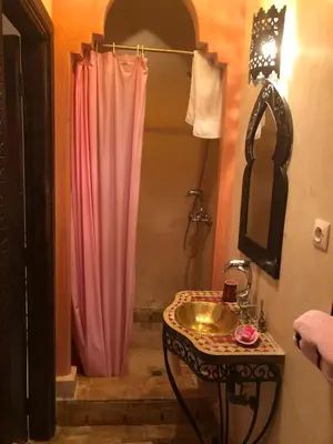 a bathroom with a sink and a pink shower curtain at Riad Côté palmeraie in Marrakech