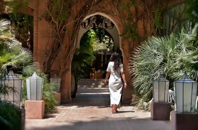 a woman walking through an archway in a garden at Dar Rhizlane, Palais Table d'hôtes & SPA in Marrakech