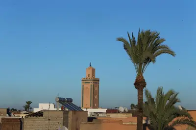a building with a clock tower and a palm tree at Riad Zehar & Spa Marrakech in Marrakech