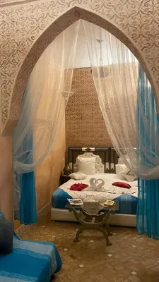 a bedroom with a bed with curtains and a table at Riad Rêves D'orient & Spa in Marrakech