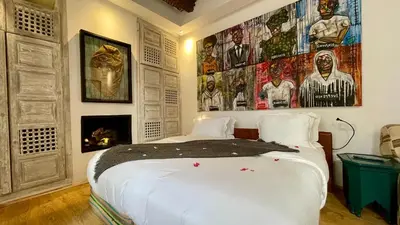 a bedroom with a large white bed and a fireplace at BCK Art Riad in Marrakech