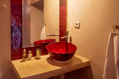 a bathroom with a red sink and a mirror at Riad Les Jardins des Lilas in Marrakech
