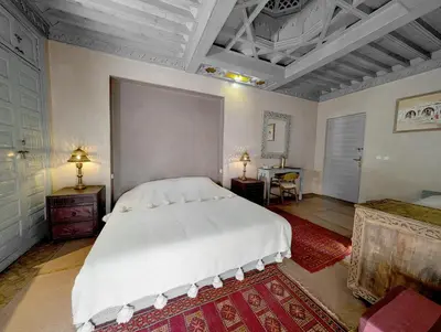 a bedroom with a large white bed and a table at Riad Slitine & Spa in Marrakech