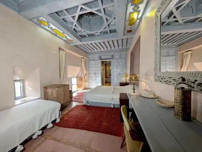 a bedroom with two beds and a table and a mirror at Riad Slitine & Spa in Marrakech