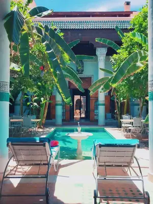 a swimming pool with two chairs and a fountain at Riad Slitine & Spa in Marrakech