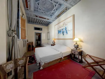 a bedroom with a white bed and a red rug at Riad Slitine & Spa in Marrakech