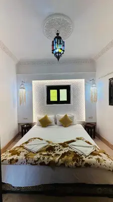 a bedroom with a large bed and a chandelier at Riad 46 in Marrakech