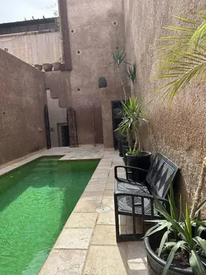a swimming pool with chairs and plants in a courtyard at Villa Makassar in Marrakech