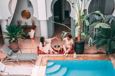 a group of three people sitting next to a swimming pool at Riad Shemsi in Marrakech