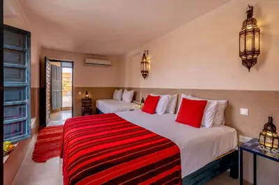 a bedroom with two beds with red pillows at Hotel & Spa Dar Sara in Marrakech